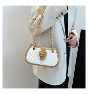 Détail d'un sac à chaîne matelassé en V blanc et marron sur un blazer beige