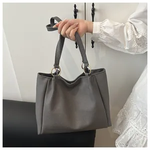 Detail of dark grey tote bag featuring fabric texture, gold hardware and shoulder strap