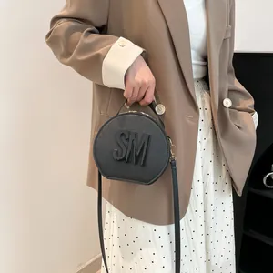 Stylish black circular handbag with SM letter logo and adjustable shoulder strap