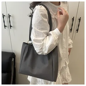 Detail of dark grey canvas tote bag with gold ring buckle on model wearing lace dress