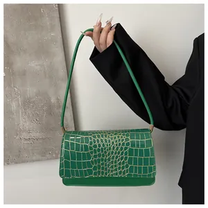Détail de la texture crocodile verte sur sac bandoulière en similicuir et boucles dorées