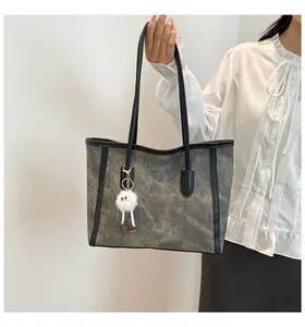 Detail of dark grey tote bag with marble texture and plush monster bag charm