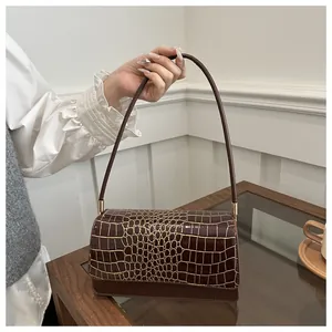 Gros plan d'un sac en cuir marron motif crocodile avec boucles dorées élégantes