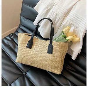 Close-up of woven straw tote bag with black leather handles on an elegant chair