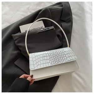 Vue détaillée d'un sac à main blanc motif crocodile sur blazer gris, style urbain minimaliste