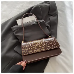 Détail du rabat en relief crocodile marron foncé et des ferrures dorées sur le sac à main