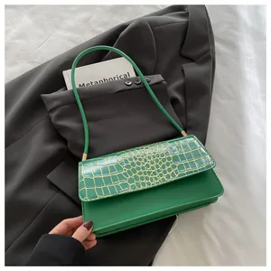 Détail du rabat en cuir de crocodile vert sur un petit sac à main brillant moderne