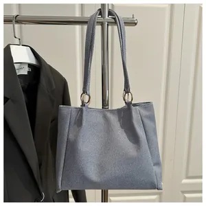 Close-up of greyish-blue twilled fabric texture and golden metal rings on a tote bag