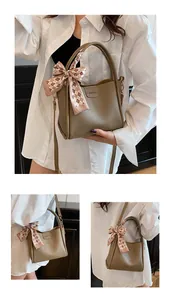 Close-up of khaki litchi grain leather bucket bag with fashion label and silk scarf detail