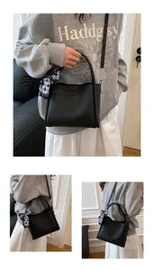 Detail of black lychee grain leather bucket bag featuring a decorative checkered scarf