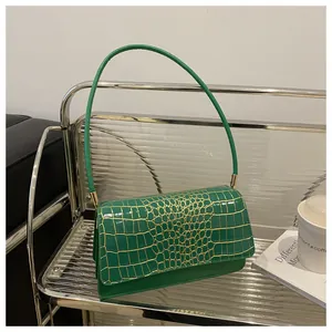 Détail d'un sac à main vert à motif crocodile sur une étagère avec un décor moderne