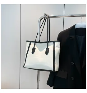 Detail of a large contrast tote bag in cream canvas and black leather on a hanger