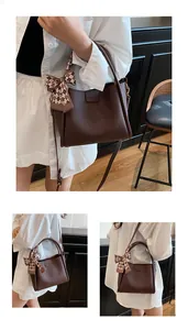Detailed macro view of dark coffee lychee grain leather bucket bag with silk scarf detail