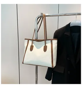 Detail of canvas tote bag with brown leather trim hanging with a black blazer