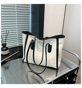 Detail view of a spacious black and white canvas tote bag in a minimalist home setting