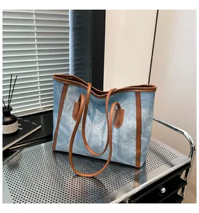 Detail of vintage denim tote bag featuring blue fabric and contrast brown leather trim