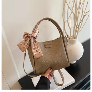 Close-up of brown litchi pattern bucket bag with a stylish checkered silk ribbon detail