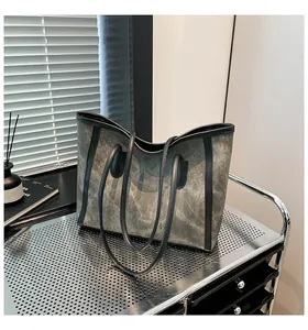 Close-up of vintage grey canvas tote bag with black leather trim on a metal shelf