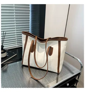 Detail of canvas tote bag with brown leather trim on industrial metal shelf display