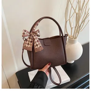 Detail of dark brown lychee leather bucket bag with silk scarf and fashion stamp