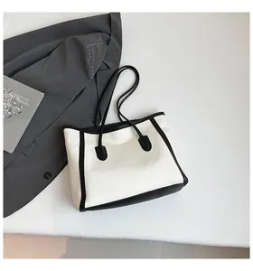 Detailed top view of a contrast black and white tote bag on a grey suit background
