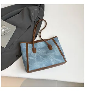 Detailed overhead view of the light blue denim tote bag with brown leather trim and shoulder strap