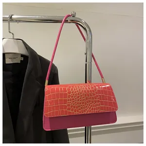 Détail du sac sous le bras en cuir de crocodile rose avec garnitures dorées