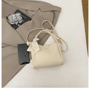 Detail of beige lychee leather bucket bag with silk scarf handle and golden hardware