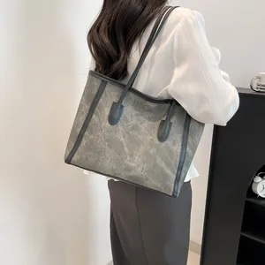 Retro grey canvas tote bag with black leather trim worn by a model in a minimalist setting