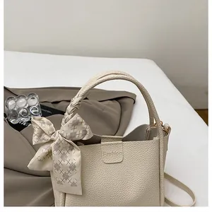 Detail of beige lychee pattern bucket bag with woven handle and silk scarf decor