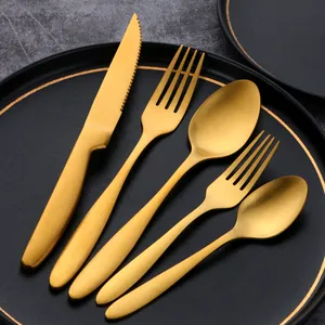 Modern 5-piece matte gold stainless steel cutlery set arranged on a black luxury plate