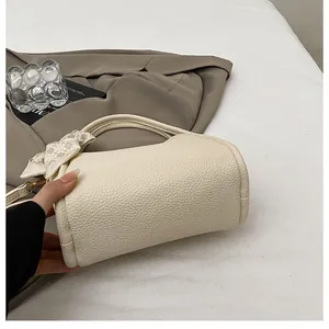 Detail of cream white bucket bag with pebble leather texture and plaid bow decoration