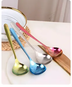 Détail de quatre cuillères à soupe colorées en titane mat avec texture étoilée sur marbre