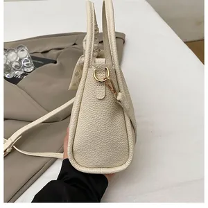 Detail of beige bucket bag with lychee texture leather and decorative silk scarf accessory