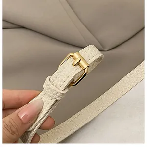Detailed close-up of cream leather shoulder strap with lychee texture and gold metal buckle
