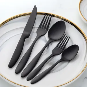 Close-up of a 5-piece matte black stainless steel cutlery set on a marble plate