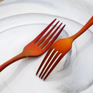 Detailed macro view of two orange gradient stainless steel forks on marble plate