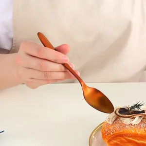 Close-up of rose gold stainless steel dessert spoon held over a creamy cake dessert