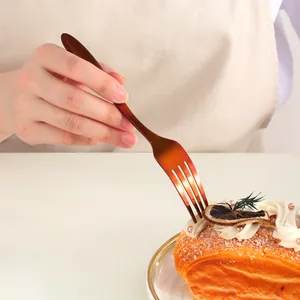 Detail shot of a bronze-toned stainless steel dessert fork held over a gourmet cake