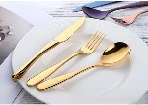 Detail of gold stainless steel cutlery set with mirror polish on a white plate