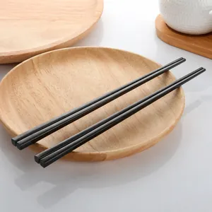 Detail view of modern black heat-resistant chopsticks on a minimalist wooden tray
