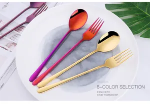 Vue détaillée d'un ensemble cuillère et fourchette en acier poli violet et doré sur assiette