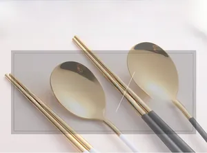 Détail macro d'une cuillère et de baguettes en acier inoxydable doré au poli miroir