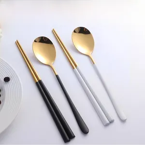 Détail d'un ensemble de couverts portables noir et blanc avec finition dorée et sac de rangement