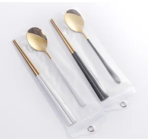 Détail d'un ensemble de couverts portable avec cuillères dorées et poignées mates colorées