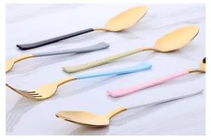 Détail de couverts 304 plaqués or avec manches colorés sur fond de marbre blanc