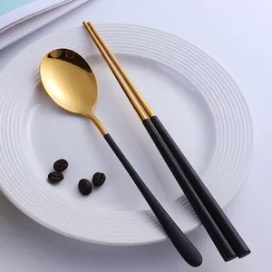 Set de voyage cuillère et baguettes en acier inoxydable doré et noir sur une assiette blanche