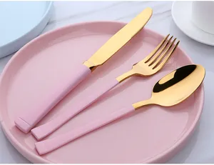 Détail macro de couverts en acier inoxydable doré avec manches roses sur une assiette