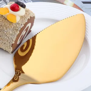 Golden stainless steel cake server with serrated edge and mirror finish on white plate
