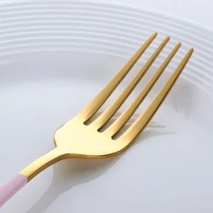 Fourchette en acier inoxydable 304 dorée avec un manche rose pourpre sur une assiette blanche